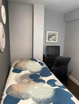 a bedroom with a bed and a desk and a television at Suite Sunrise in Vancouver