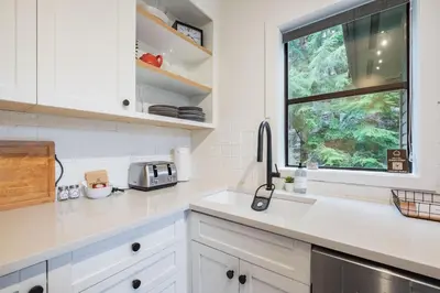 a kitchen with white cabinets and a window at Powderview 24 by Outpost Whistler in Whistler