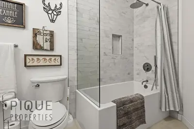 a bathroom with a shower and a toilet and a tub at Mountain Haven Retreat, Pool & Hot Tub, UG Parking, Fitness Centre, WiFi! in Canmore