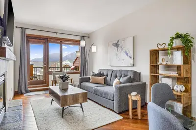 a living room with a couch and a table at Alluring Mountain View Condo - Right In The Heart Of Downtown - managed by Little Sister Getaways in Canmore