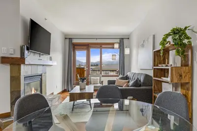 a living room with a glass table and a fireplace at Alluring Mountain View Condo - Right In The Heart Of Downtown - managed by Little Sister Getaways in Canmore
