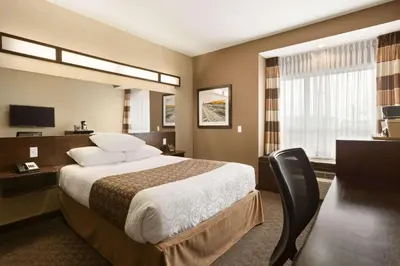 a hotel room with a large bed and a desk at Microtel Inn & Suites by Wyndham Blackfalds in Blackfalds
