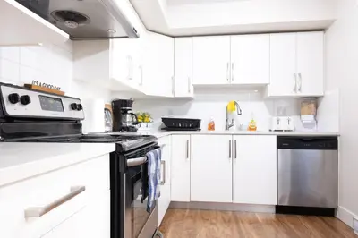 a kitchen with white cabinets and a stove top oven at Modern yet comfy 3 bed suite in Surrey in Surrey