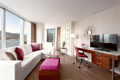 a living room with a white couch and a desk at Auberge Vancouver Hotel in Vancouver