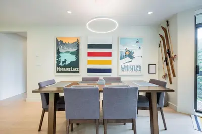 a dining room with a table with chairs and posters at Ravencrest by Outpost Whistler in Whistler