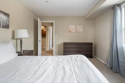 a bedroom with a white bed and a dresser at Lookout Pointe, Lakeview, Pool, Hot Tub, Gym in Invermere