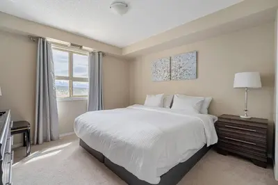 a bedroom with a large white bed and a window at Lookout Pointe, Lakeview, Pool, Hot Tub, Gym in Invermere