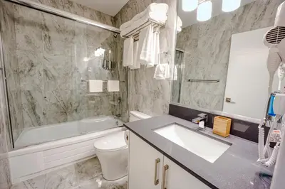 a bathroom with a sink and a tub and a toilet at Harrison Grand Motel in Harrison Hot Springs