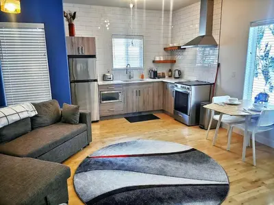 a living room with a couch and a kitchen at LuxQuarters Kitimat River Suite in Kitimat