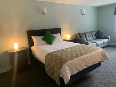 a bedroom with a large bed and a couch at Orchard View Motel in Keremeos