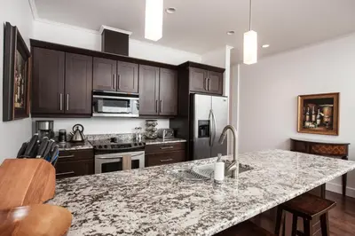 a kitchen with a marble counter top and wooden cabinets at Alpenglow Penthouse by Revelstoke Vacations in Revelstoke