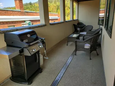 a screened in porch with a stove and chairs at Alpenglow Penthouse by Revelstoke Vacations in Revelstoke