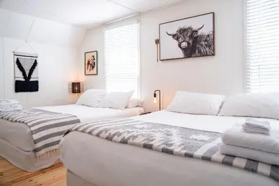 a bedroom with two beds and a picture of a cow at The Downtown Hive by Revelstoke Vacations in Revelstoke