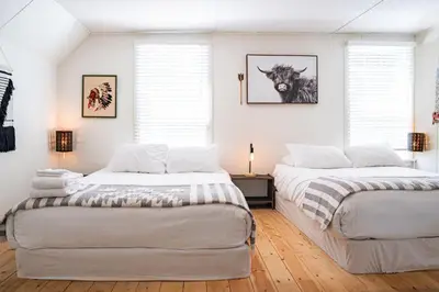 two beds in a room with white walls and windows at The Downtown Hive by Revelstoke Vacations in Revelstoke