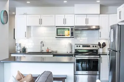 a kitchen with white cabinets and stainless steel appliances at RendezView by Revelstoke Vacations in Revelstoke