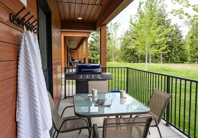 a screened porch with a table and a grill at RendezView by Revelstoke Vacations in Revelstoke