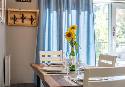 a dining room table with a vase with a sunflower on it at Pillow Top Condo by Revelstoke Vacations in Revelstoke