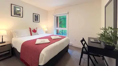 a bedroom with a bed and a desk and a window at Al's Escape by Revelstoke Vacations in Revelstoke