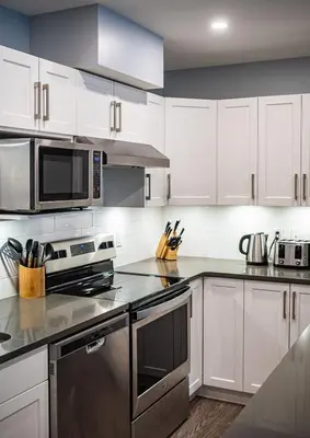 a kitchen with white cabinets and stainless steel appliances at Al's Escape by Revelstoke Vacations in Revelstoke