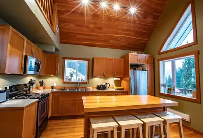 a kitchen with wooden cabinets and a wooden table at Stoke Cabin by Revelstoke Vacations in Revelstoke