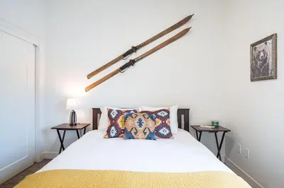 a bedroom with a white bed with two tables at The Mac Shack by Revelstoke Vacations in Revelstoke