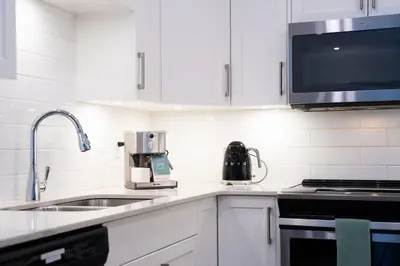 a kitchen with white cabinets and a sink and a microwave at Powder Village Retreat by Revelstoke Vacations in Revelstoke