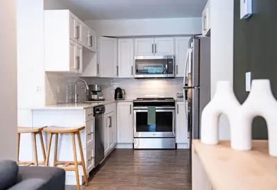 a kitchen with white cabinets and stainless steel appliances at Powder Village Retreat by Revelstoke Vacations in Revelstoke