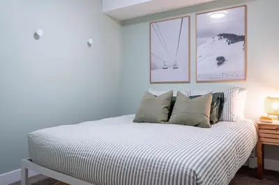 a bedroom with a bed with two pictures on the wall at Powder Village Retreat by Revelstoke Vacations in Revelstoke