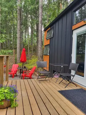 a deck with chairs and tables and a house at Forest Nook in Queens Bay
