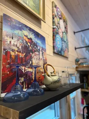 two wine glasses and a vase on a shelf with a painting at Forest Nook in Queens Bay