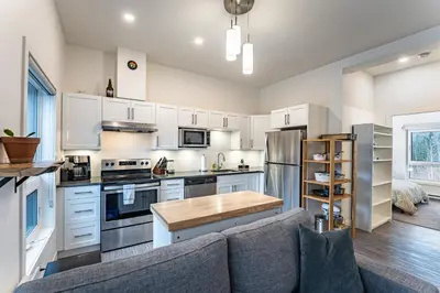 a kitchen with white cabinets and a gray couch at Niska's Den by Revelstoke Vacations in Revelstoke