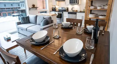 a wooden table with plates and glasses and a bottle of wine at Niska's Den by Revelstoke Vacations in Revelstoke