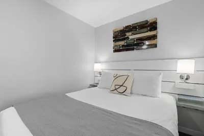 a white bedroom with a white bed and two lamps at Alpenglow Lodge Snooze Studio with Den by MVA in Whistler
