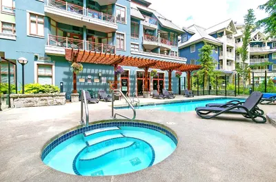 a swimming pool with two chairs and a building at Alpenglow Lodge Studio with Pool Views by MVA in Whistler