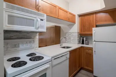 a kitchen with white appliances and wooden cabinets at Alpenglow Lodge Studio with Pool Views by MVA in Whistler