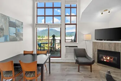 a living room with a dining room table and a fireplace at Alpenglow Lodge Junior Penthouse by MVA in Whistler