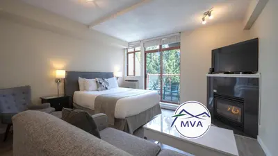 a hotel room with a bed and a tv at Alpenglow Lodge Sunny Studio with Sitting Area by MVA in Whistler
