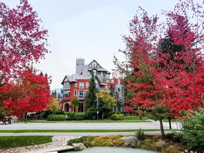 a large building with red trees in front of it at Alpenglow Lodge Sunny Studio with Sitting Area by MVA in Whistler
