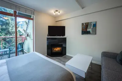 a bedroom with a bed and a fireplace at Alpenglow Lodge Sunny Studio with Sitting Area by MVA in Whistler