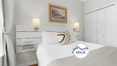 a bedroom with a white bed with a nva logo on it at Alpenglow Lodge Junior One Bedroom by MVA in Whistler