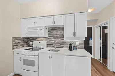 a white kitchen with white cabinets and a sink at Alpenglow Lodge Studio with park view by MVA in Whistler