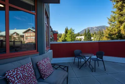 a balcony with a couch and a table and chairs at Alpenglow Lodge Large Studio with Dedicated Work Space by MVA in Whistler