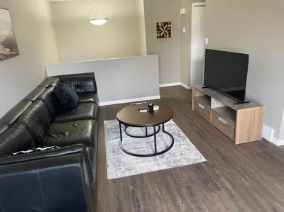 a living room with a leather couch and a table at Spacious 2-bedroom apartment in Camrose