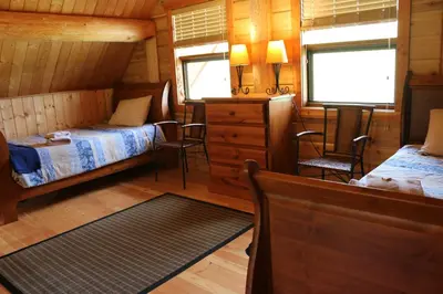 a bedroom with two beds and chairs in a cabin at Bear Valley Highlands in Lumby