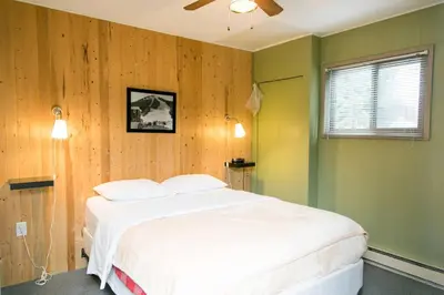 a bedroom with a white bed and wooden walls at Lone Star Motel in Rossland