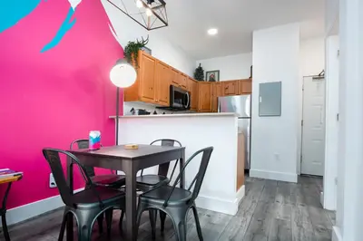 a kitchen with a table and chairs and a pink wall at The Après, Village Studio with Hot Tub and View in Whistler