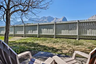 a fence with two benches in a yard with mountains at The Norquay, Pet-Friendly 2 Bed with Mtn View in Canmore