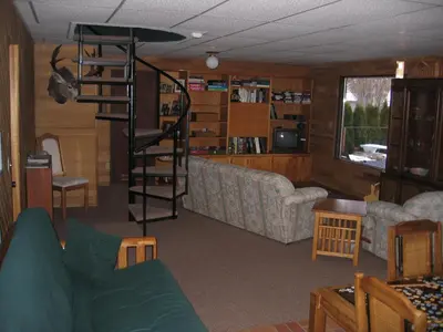 a living room with a couch and a spiral staircase at Kamloops Log Home Bed and Breakfast in Kamloops