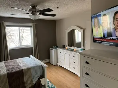 a bedroom with a bed and a flat screen tv at Chris Cozy Condo Commonwealth #205 Edmonton in Edmonton