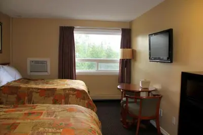 a hotel room with a bed and a table and a window at Acorn Motel in Grande Cache